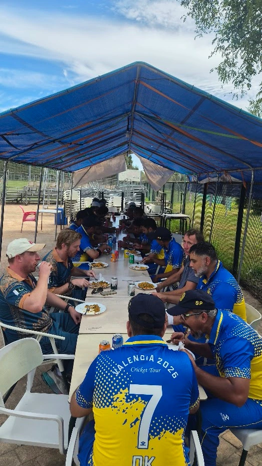 Cricket team sharing a meal under a canopy