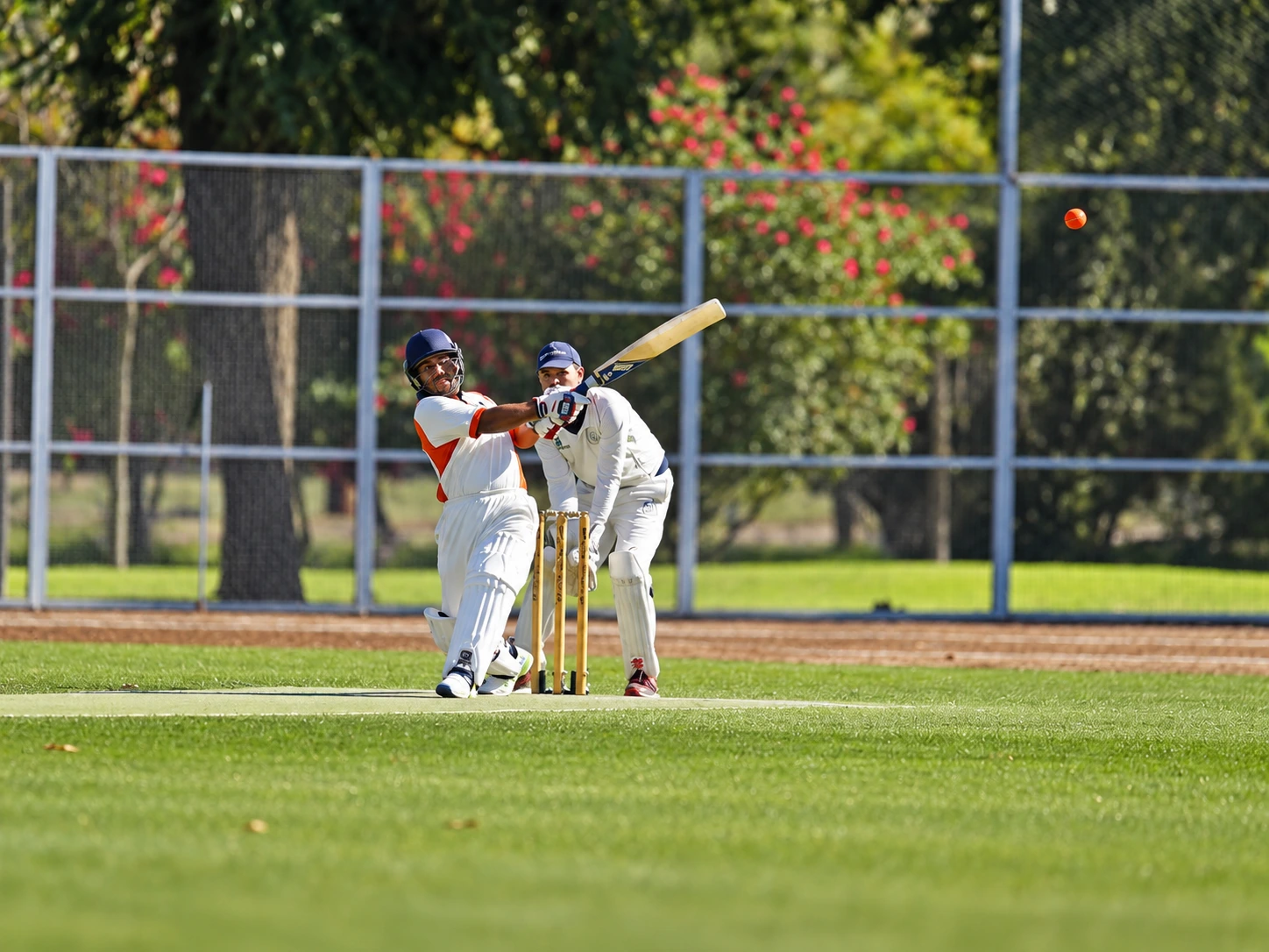 Batsman playing a shot as the wicketkeeper watches